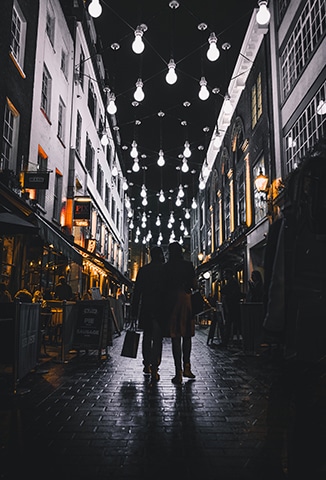 Couple walking through alleyway with lights